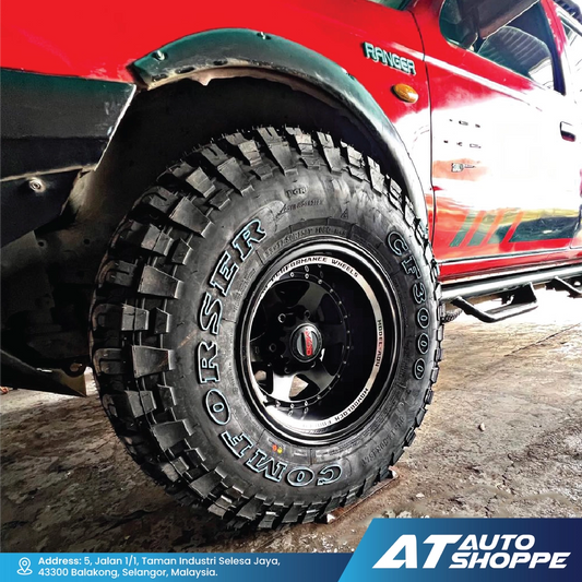 Close-up of a Comforser tire on a red vehicle with 'AT Auto Shoppe' branding.