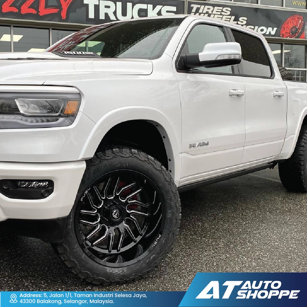 White Ram truck with black wheels parked in front of a tire store.