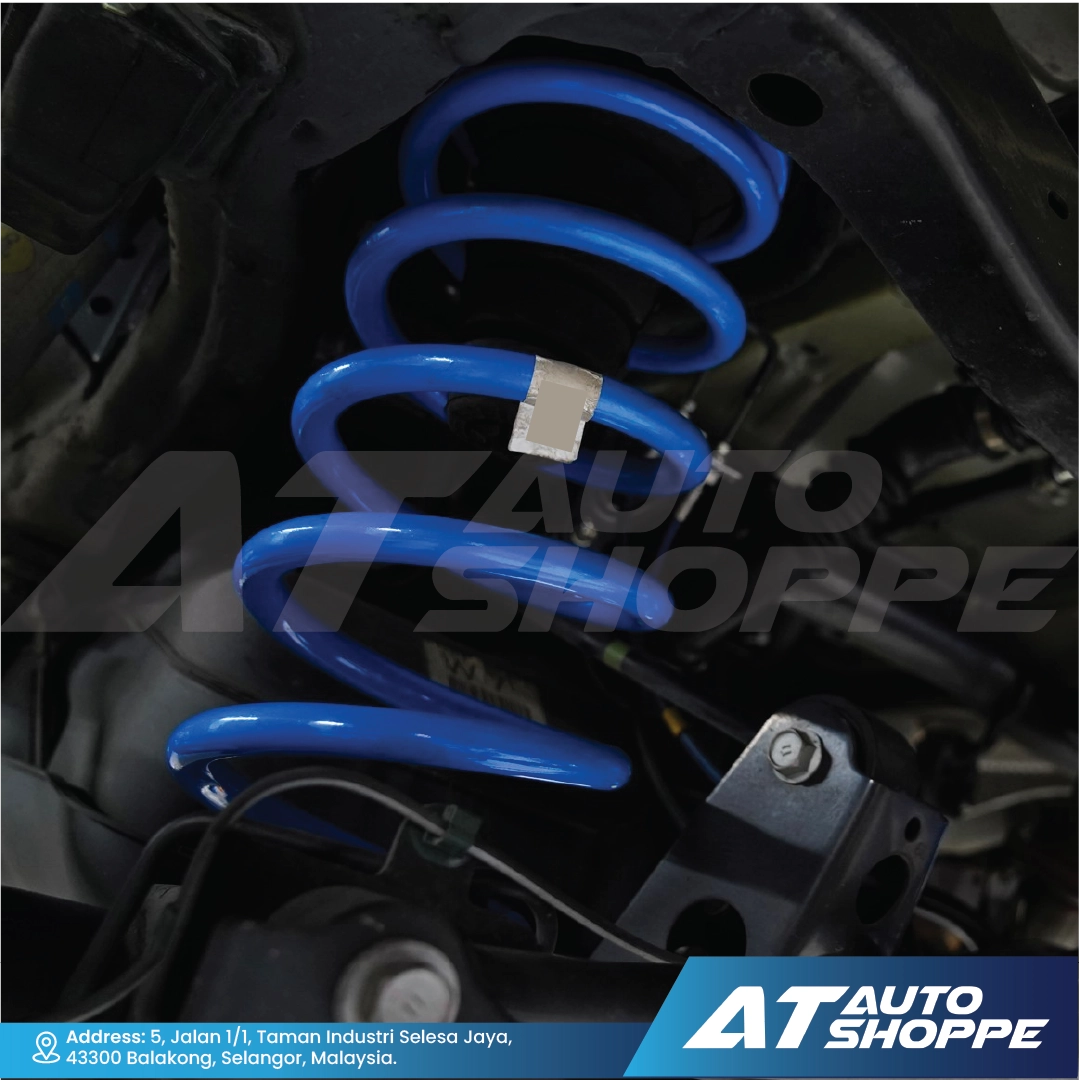 Blue shock absorber on a car suspension system with AT Auto Shoppe branding.