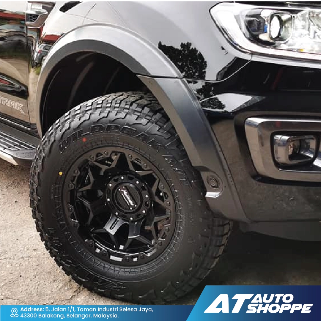 Close-up of a black tire and Monsterims wheel on a vehicle with 'AT Auto Shoppe' branding.