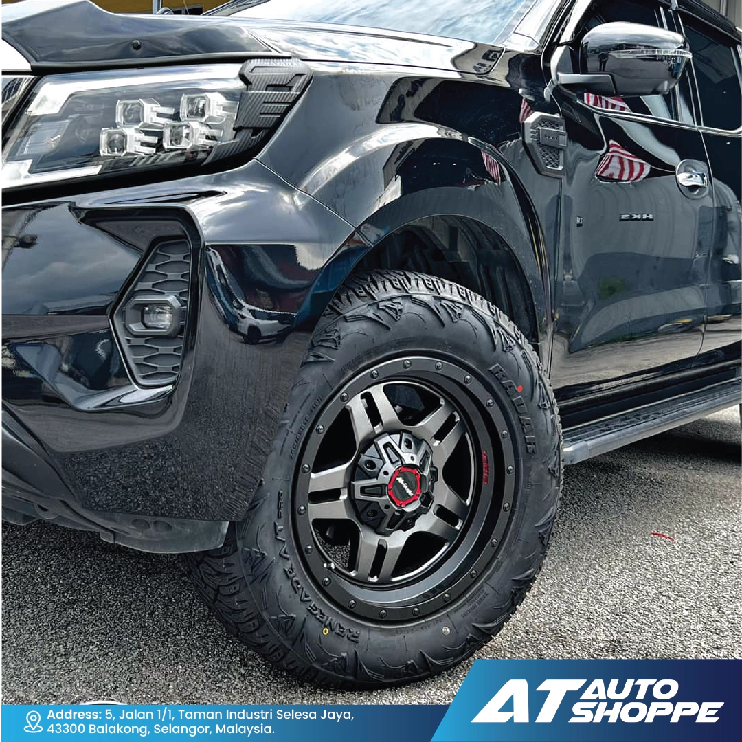 Close-up of a black truck featuring a Monsterims wheel, with the AT Auto Shoppe logo.