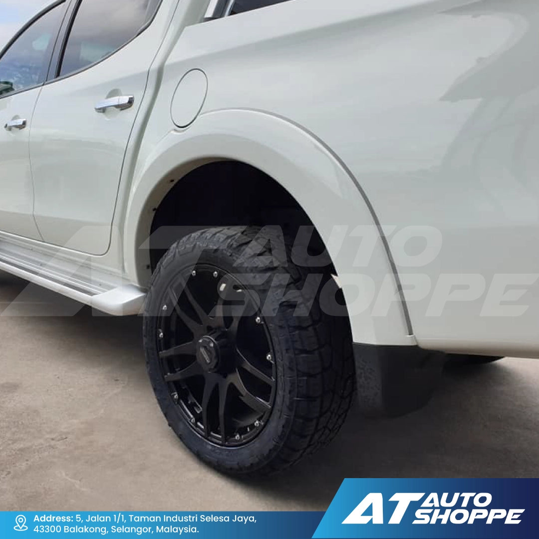 Close-up of a white car with a black wheel, showing the AT Auto Shoppe branding.