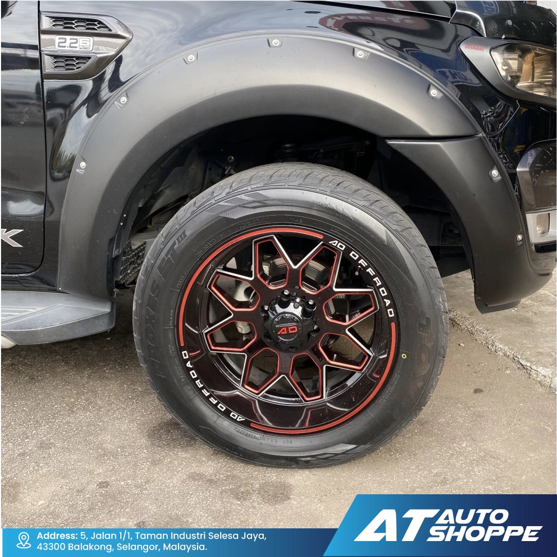 Close-up of a car tire with red accents on a vehicle, featuring the AT Auto Shoppe logo.