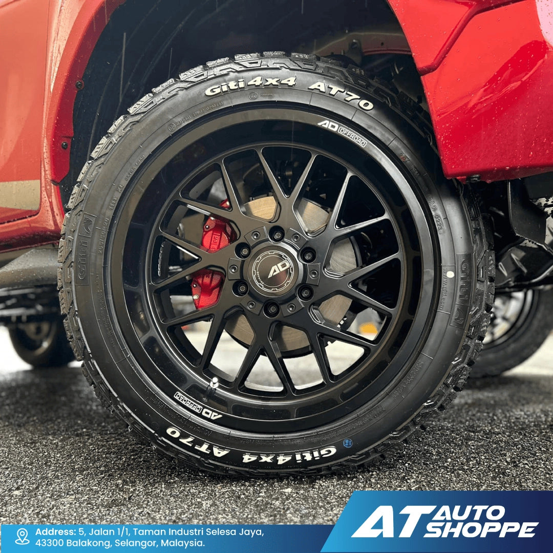 Close-up of a red vehicle's wheel with black rim and tire, featuring 'AD Wheels' branding. AT Auto Shoppe logo visible.