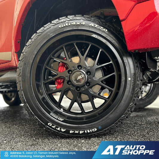 Close-up of a red vehicle's wheel with black rim and tire, featuring 'AD Wheels' branding. AT Auto Shoppe logo visible.