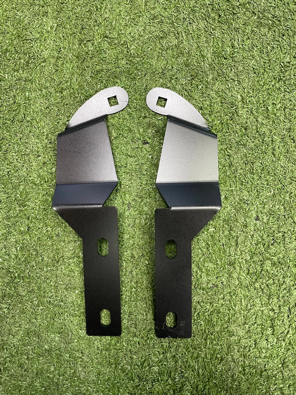 Two metal brackets on a green grass background