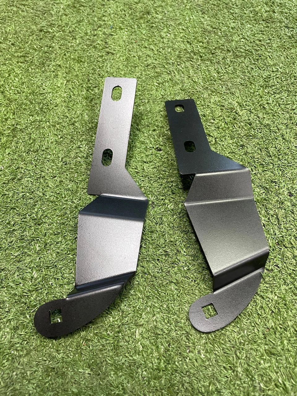 Two metal brackets on a green grass background