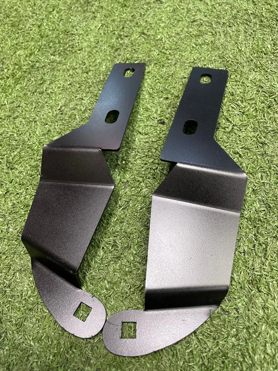 Two metal brackets on a green grass background