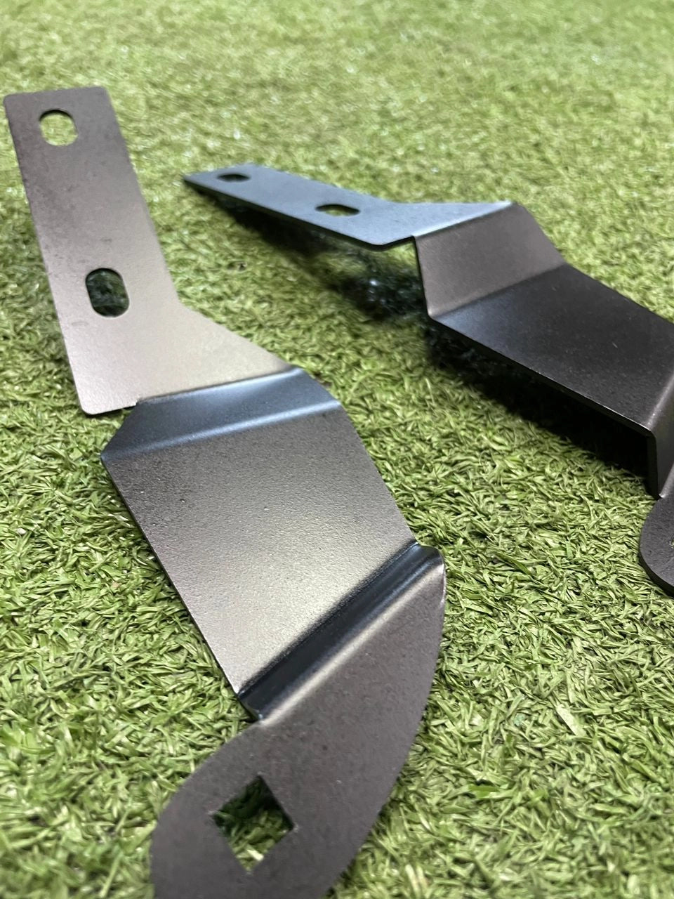 Two metal brackets on a green grass background