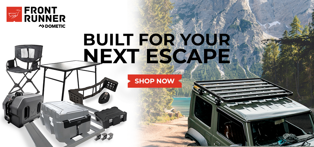 Front Runner Dometic outdoor gear setup including storage boxes, camping table and accessories with off-road vehicle in mountain landscape