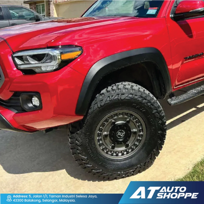 Red Toyota Tacoma truck with off-road tires on a driveway, featuring AT Auto Shoppe branding.