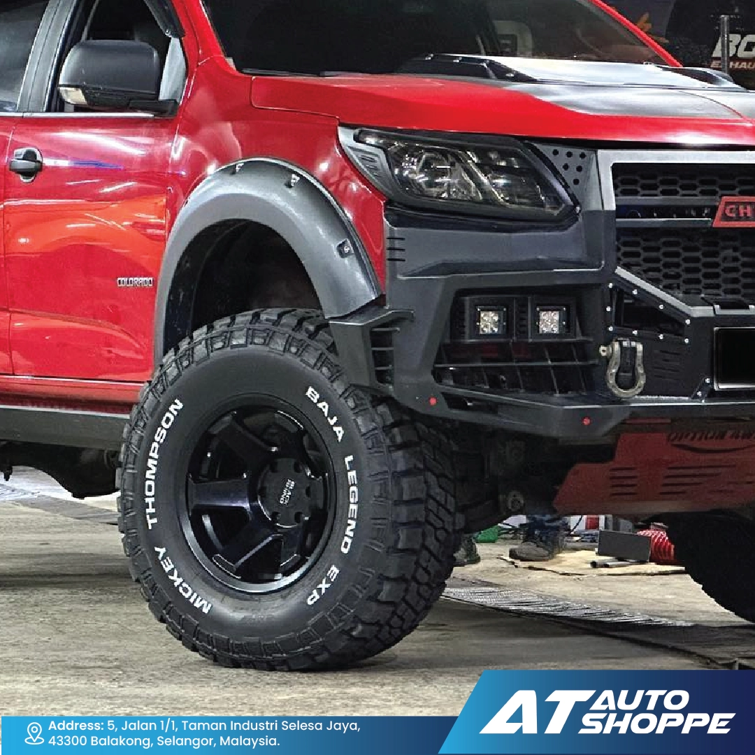Red truck with large off-road tire and black rim on a concrete surface, featuring AT Auto Shoppe branding.