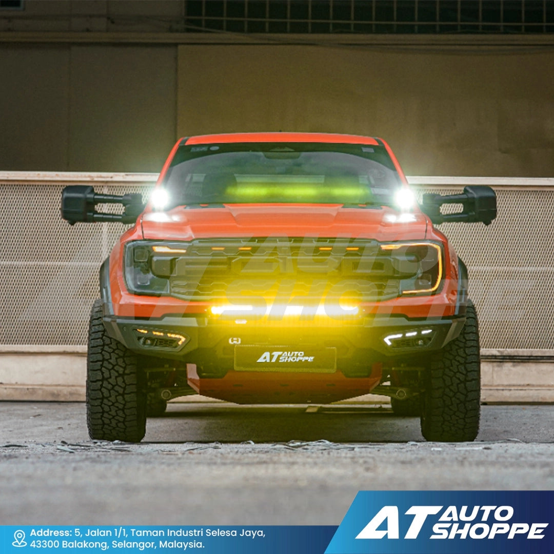 Orange truck with illuminated headlights on a concrete surface, featuring AT Auto Shoppe branding.
