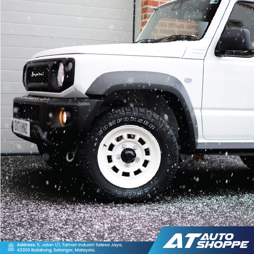 White SUV with a Comforser CF1100 black tire and white rim on a snowy road, featuring AT Auto Shoppe branding.