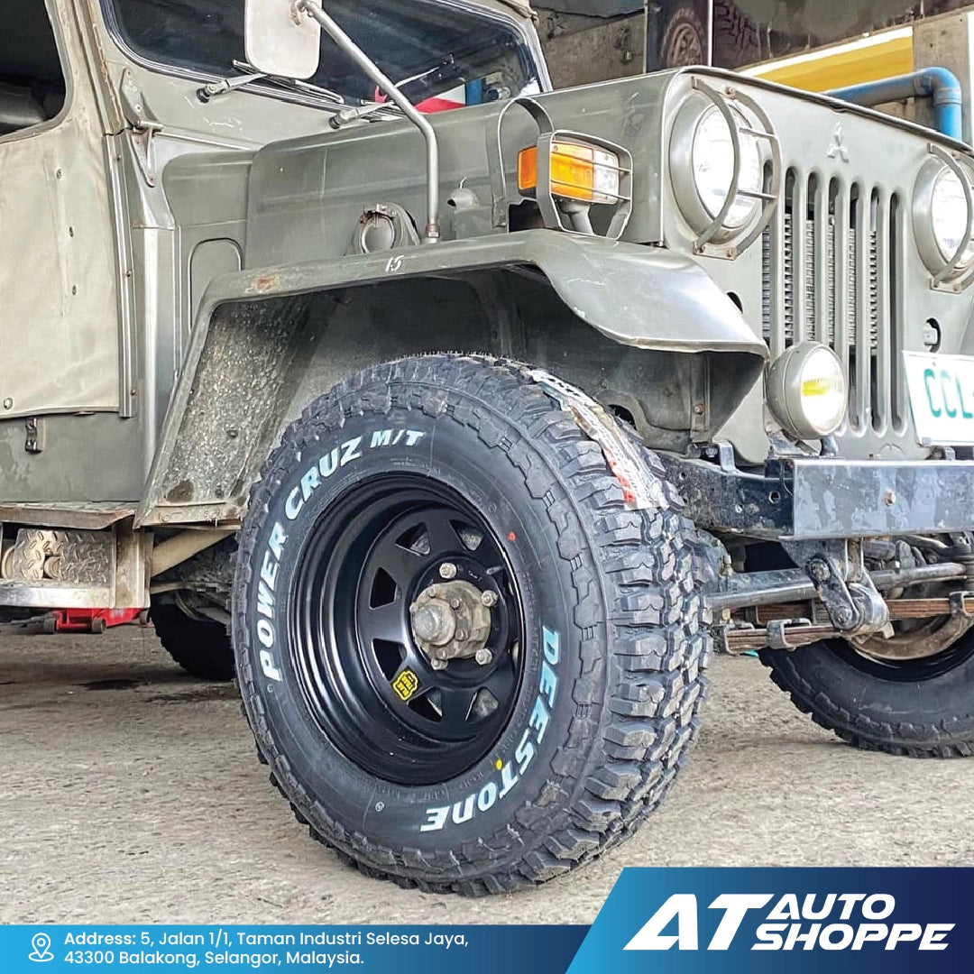 Close-up of a Jeep with a large off-road Deestone tire, featuring the brand 'AT Auto Shoppe'.