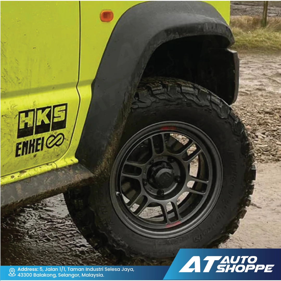 Close-up of a vehicle tire with ENKEI branding on a muddy road, featuring AT Auto Shoppe logo.