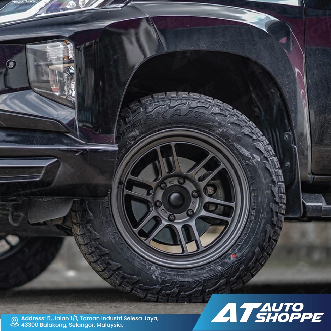 Close-up of a black truck tire with AT Auto Shoppe branding.