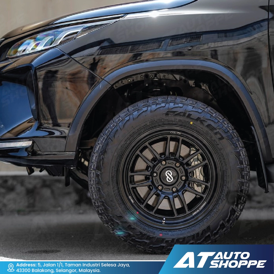 Close-up of a black vehicle wheel with a tire, featuring the AT Auto Shoppe logo.