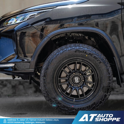 Close-up of a black vehicle wheel with a tire, featuring the AT Auto Shoppe logo.