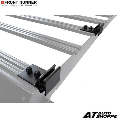 Metal roof rack system with black brackets on a white background, featuring 'Front Runner' and 'AT Auto Shoppe' logos.