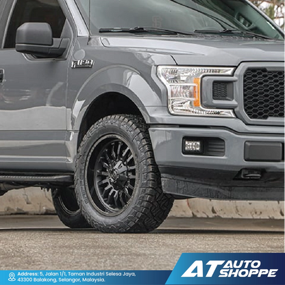 Gray pickup truck with off-road tires on a road, featuring AT Auto Shoppe branding.