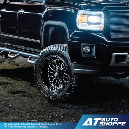 Close-up of a black truck with large off-road tires on a dark surface, featuring the AT Auto Shoppe logo.
