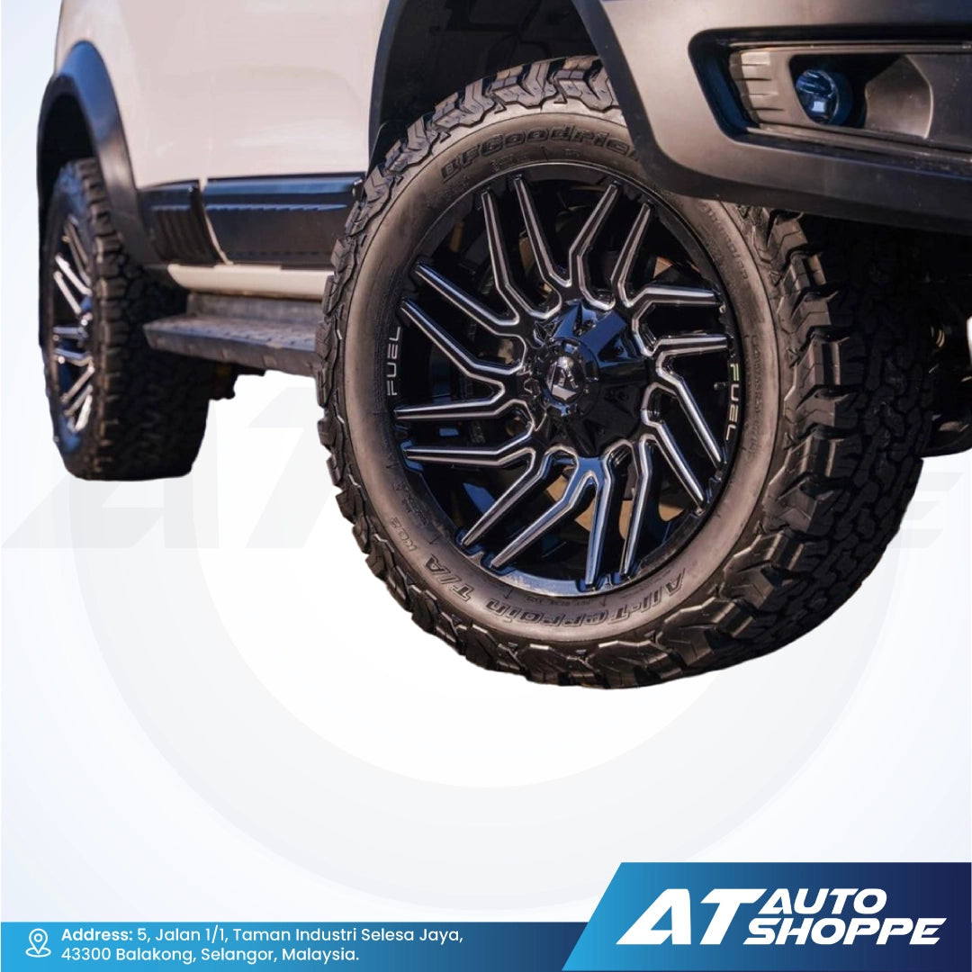 Close-up of a vehicle wheel with a visible tire and rim, featuring the AT Auto Shoppe logo.