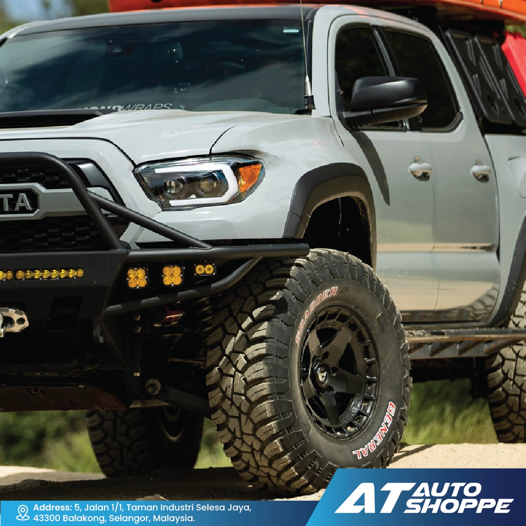 Silver Toyota truck with off-road tires and accessories, featuring AT Auto Shoppe branding.