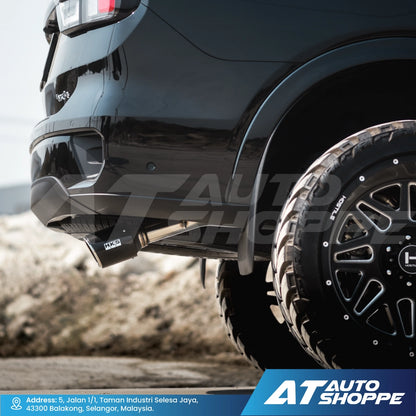 Close-up of a black vehicle with off-road tires and suspension, featuring AT Auto Shoppe branding.