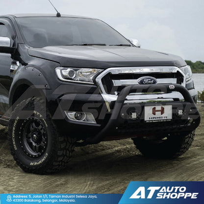 Ford truck with a front bumper guard on a dirt road, featuring AT Auto Shoppe branding.