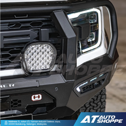 Close-up of a vehicle's front bumper with LED light and grille, branded with AT Auto Shoppe.