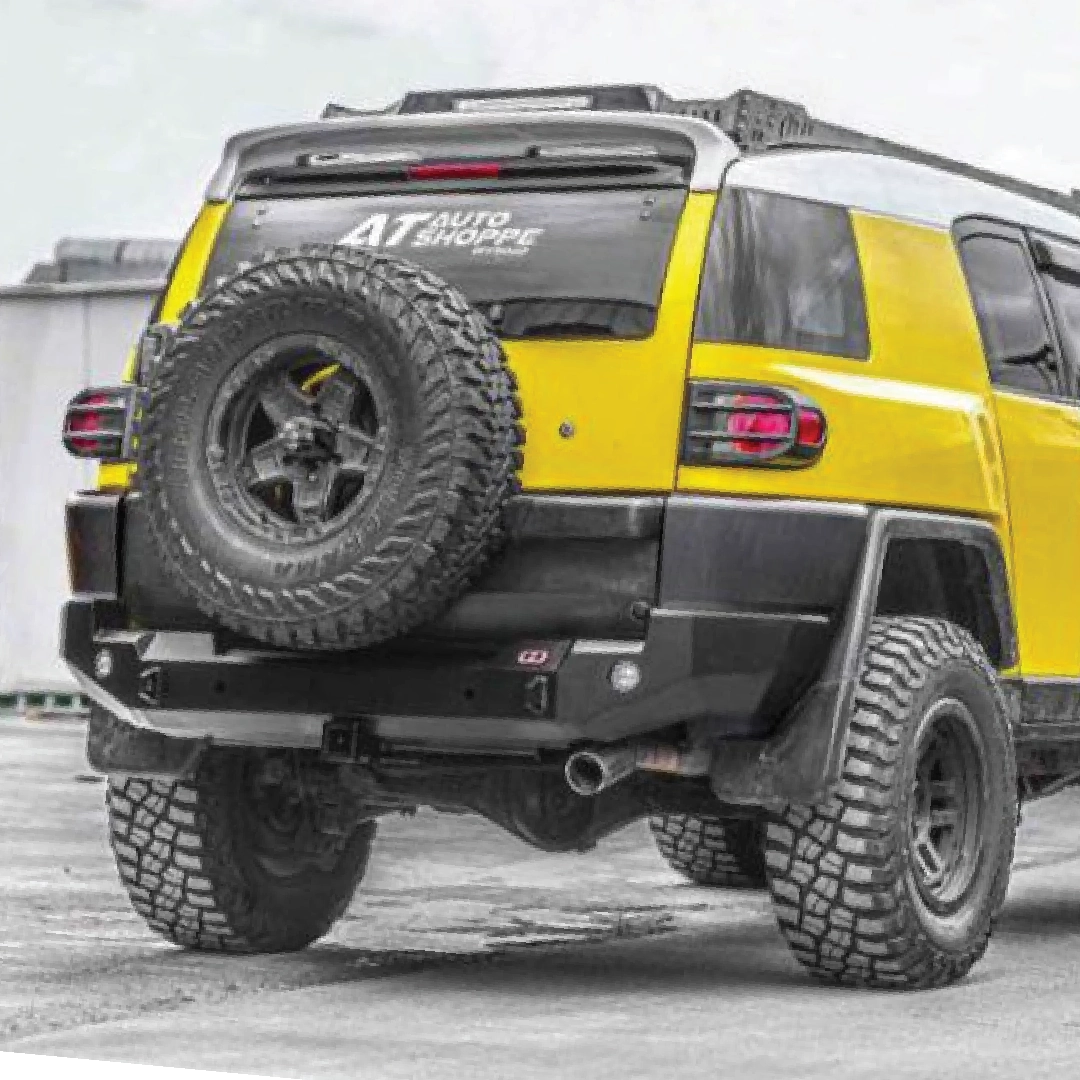 Yellow SUV with off-road tires and a spare tire mounted on the back, parked on a concrete surface.