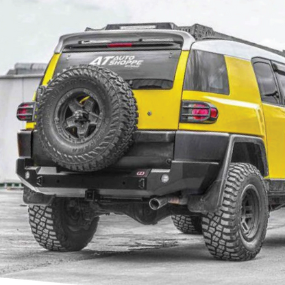 Yellow SUV with off-road tires and a spare tire mounted on the back, parked on a concrete surface.
