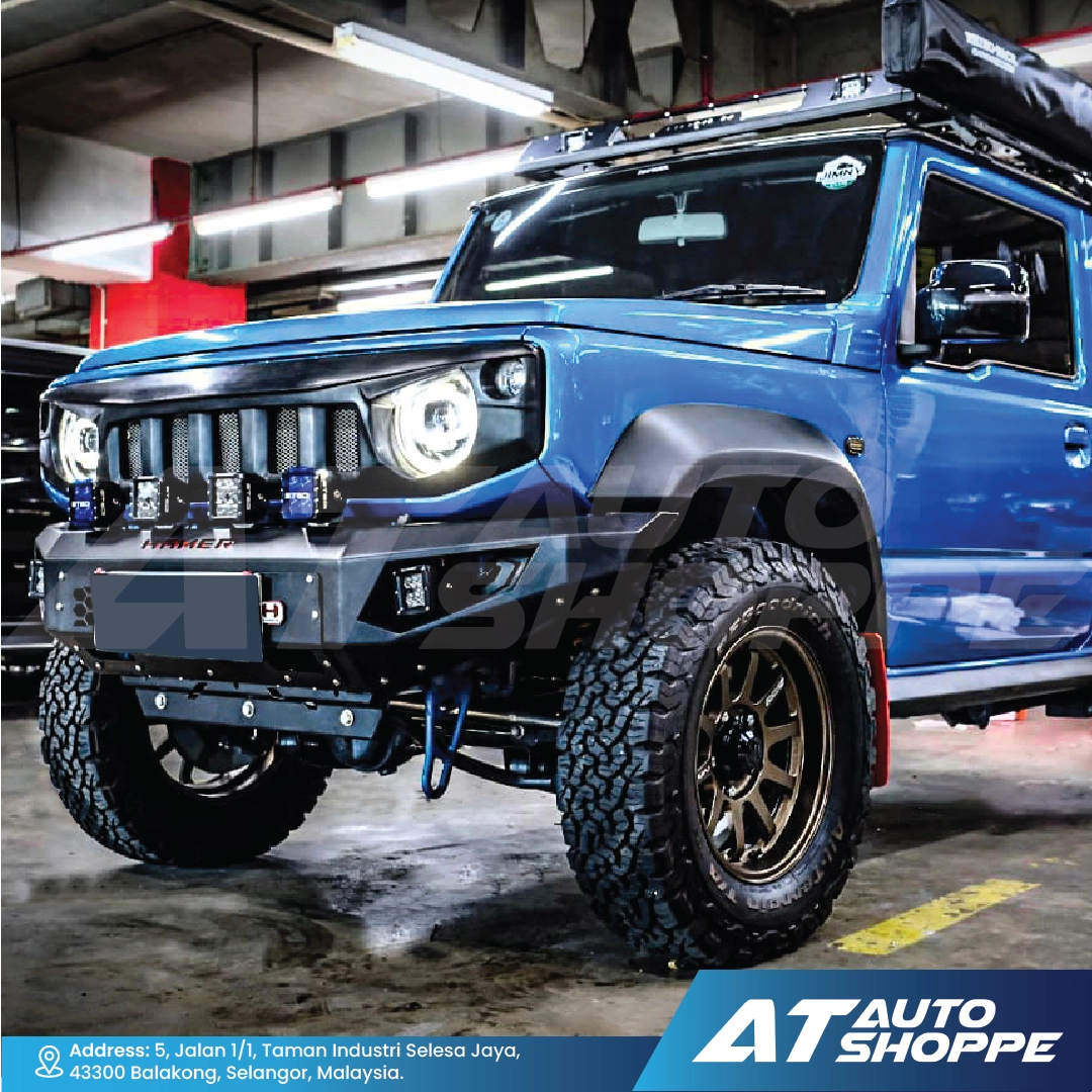 Blue off-road vehicle with additional lights in a garage, featuring AT Auto Shoppe branding.