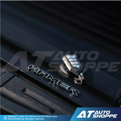 Close-up of a car door handle with 'Hamer' branding on a black surface, featuring AT Auto Shoppe logo.