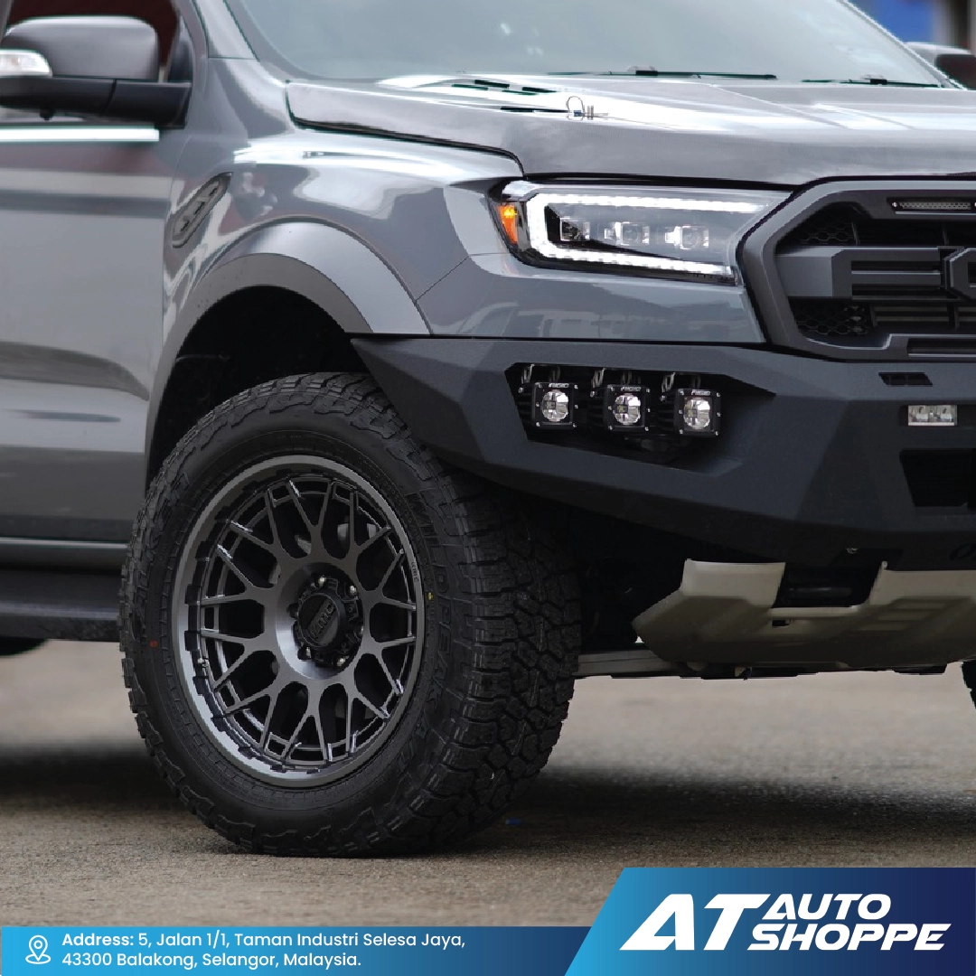 Gray pickup truck with black wheels on a road, featuring AT Auto Shoppe branding.
