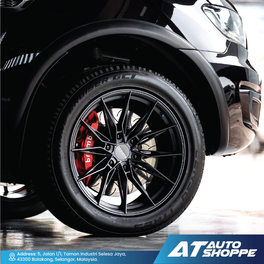 Close-up of a car wheel with black rim and red brake caliper, blurred background