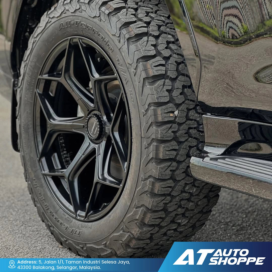 Close-up of a tire with tread pattern on a vehicle, featuring the AT Auto Shoppe logo.