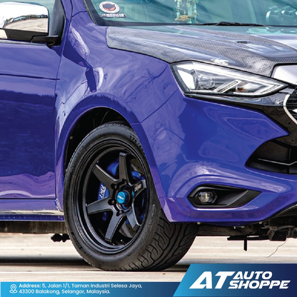 Close-up of a blue car with black rims on a road, featuring AT Auto Shoppe branding.