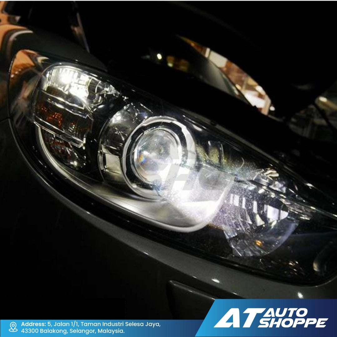 Close-up of a car headlight with 'AT Auto Shoppe' branding.