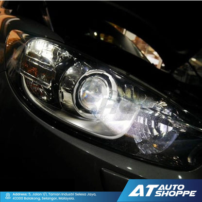 Close-up of a car headlight with 'AT Auto Shoppe' branding.