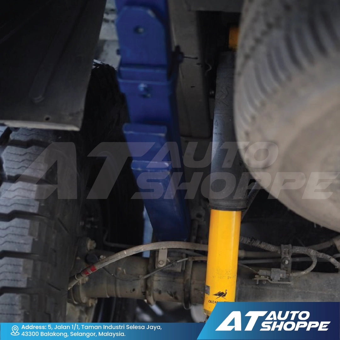 Close-up of a vehicle's suspension system with a yellow shock absorber, branded 'AT Auto Shoppe'.