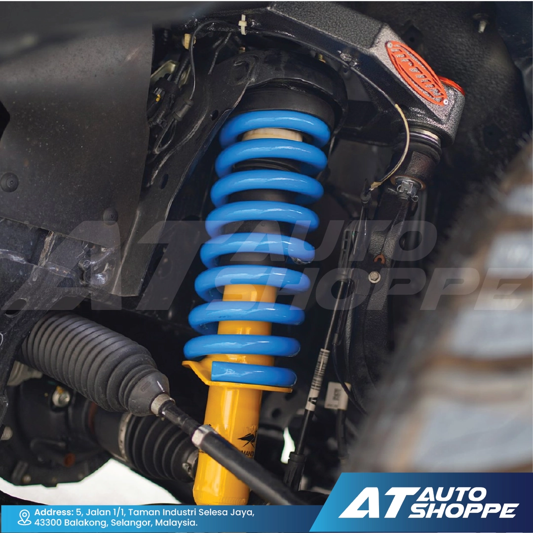 Close-up of a car suspension system with blue coil springs and AT Auto Shoppe branding.