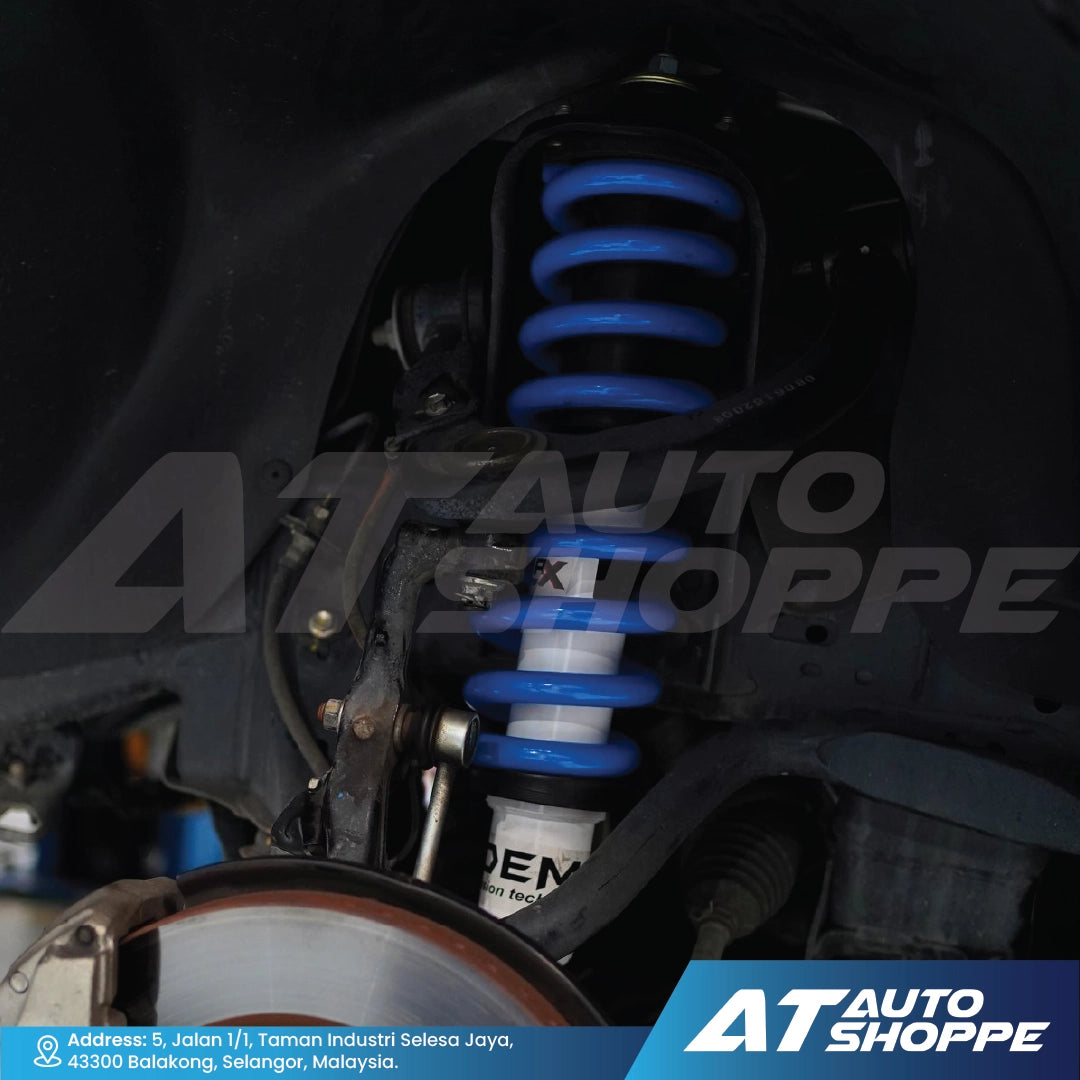 Close-up of a car suspension system with blue springs, branded 'AT Auto Shoppe'.