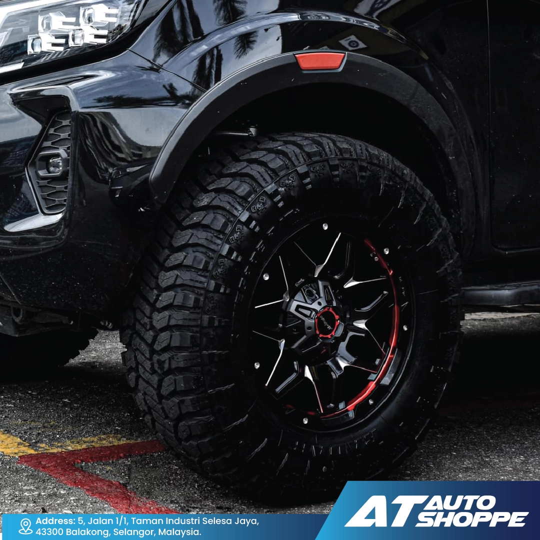 Close-up of a Monsterims wheel with red accents on a dark background, featuring the AT Auto Shoppe logo.