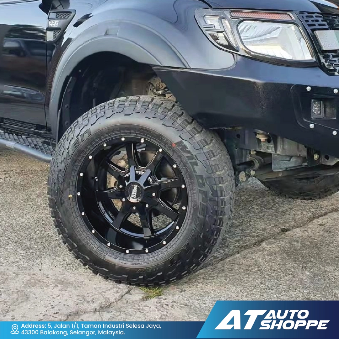 Close-up of a black off-road tire and Moto Metal rim on a vehicle, with 'AT Auto Shoppe' branding.