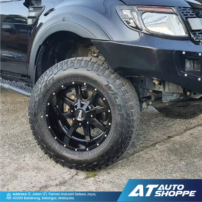 Close-up of a black off-road tire and Moto Metal rim on a vehicle, with 'AT Auto Shoppe' branding.