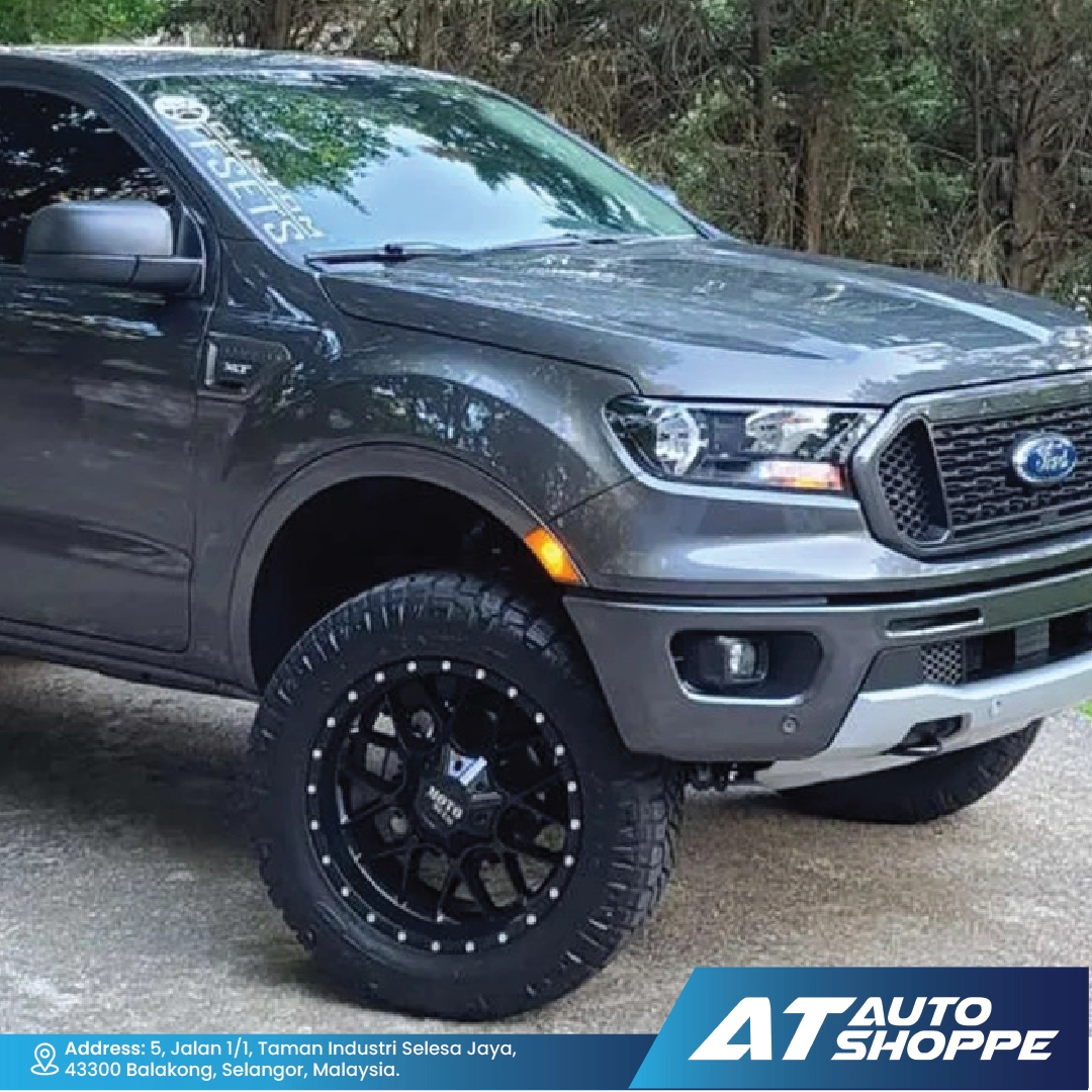 Gray Ford truck with black rims on a road, featuring AT Auto Shoppe branding.