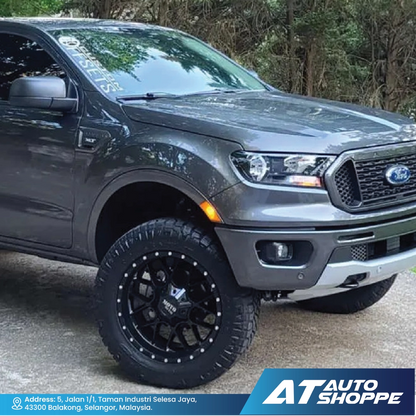 Gray Ford truck with black rims on a road, featuring AT Auto Shoppe branding.