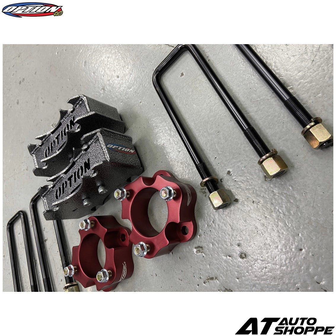 Automotive suspension components on a gray surface with 'AT Auto Shoppe' branding.